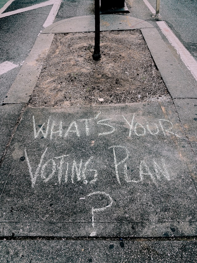 Written with chalk on a side path, "What's your voting plan?"