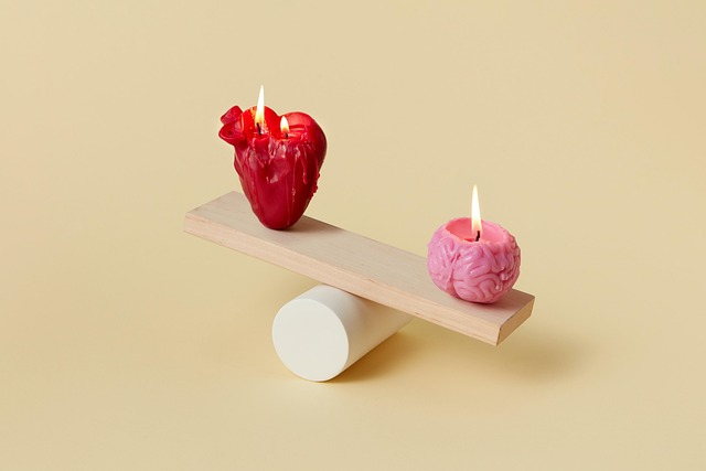 an image of two candles balancing on a sea-saw. One of the candles is a heart, the other is a brain